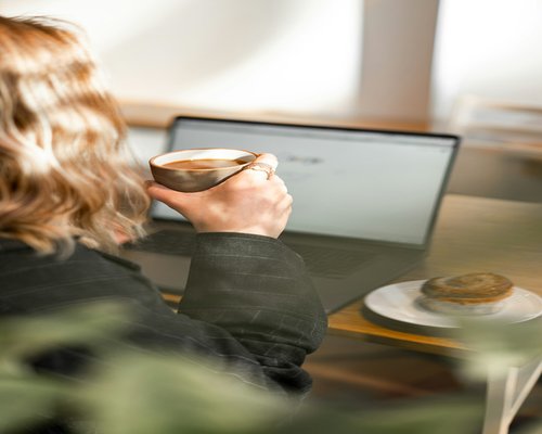 A person taking a mindful break from their laptop with a cup of coffee