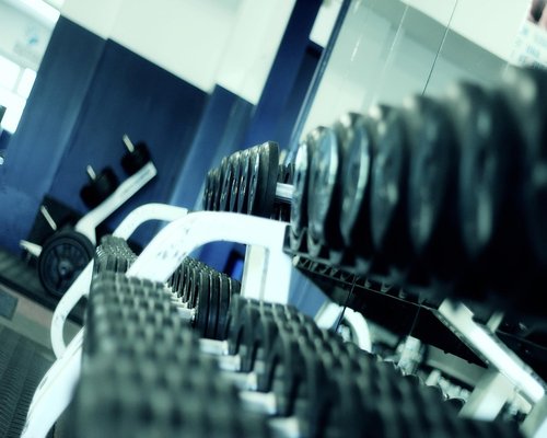 Woman lifting weights in a gym with bright artificial lighting